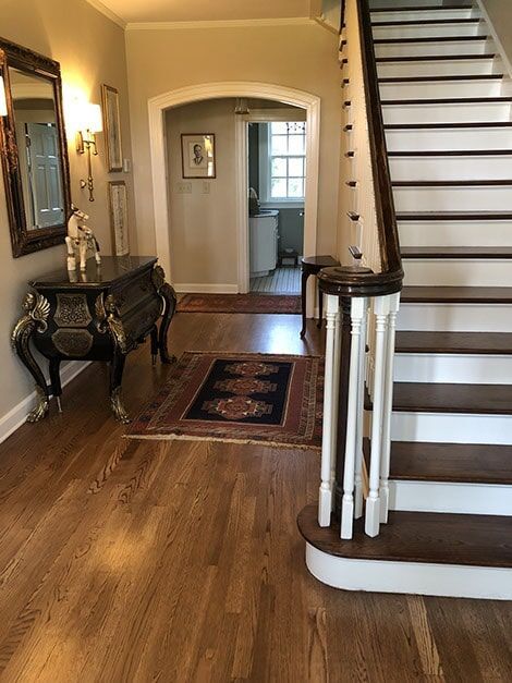 A hallway with hardwood floors and stairs in a house.