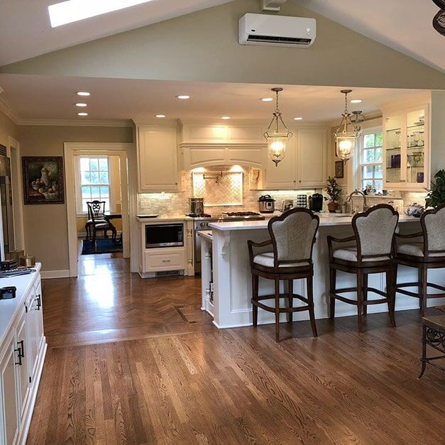 A kitchen with hardwood floors and white cabinets and stools