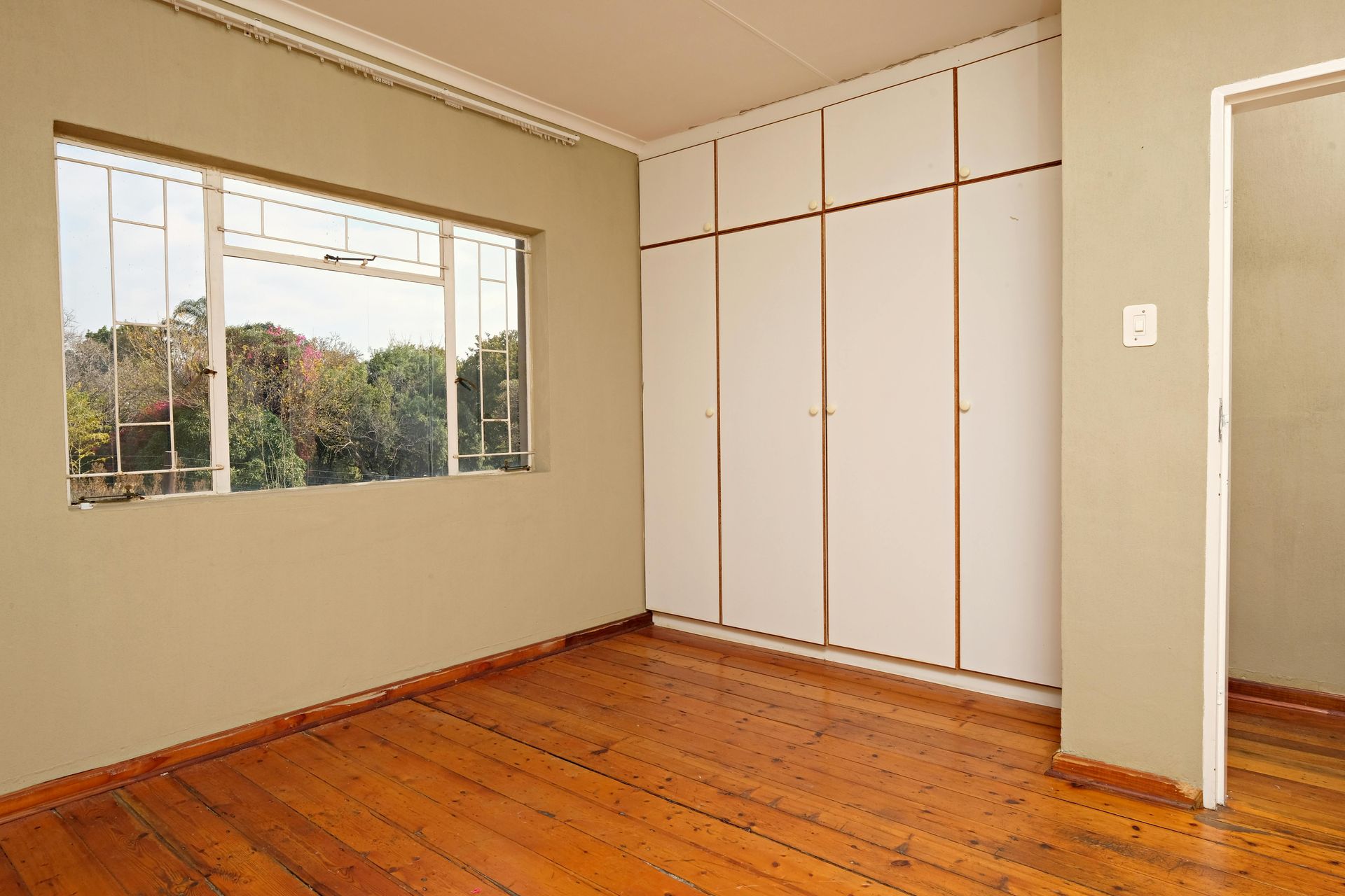 An empty room with hardwood floors and a large window.