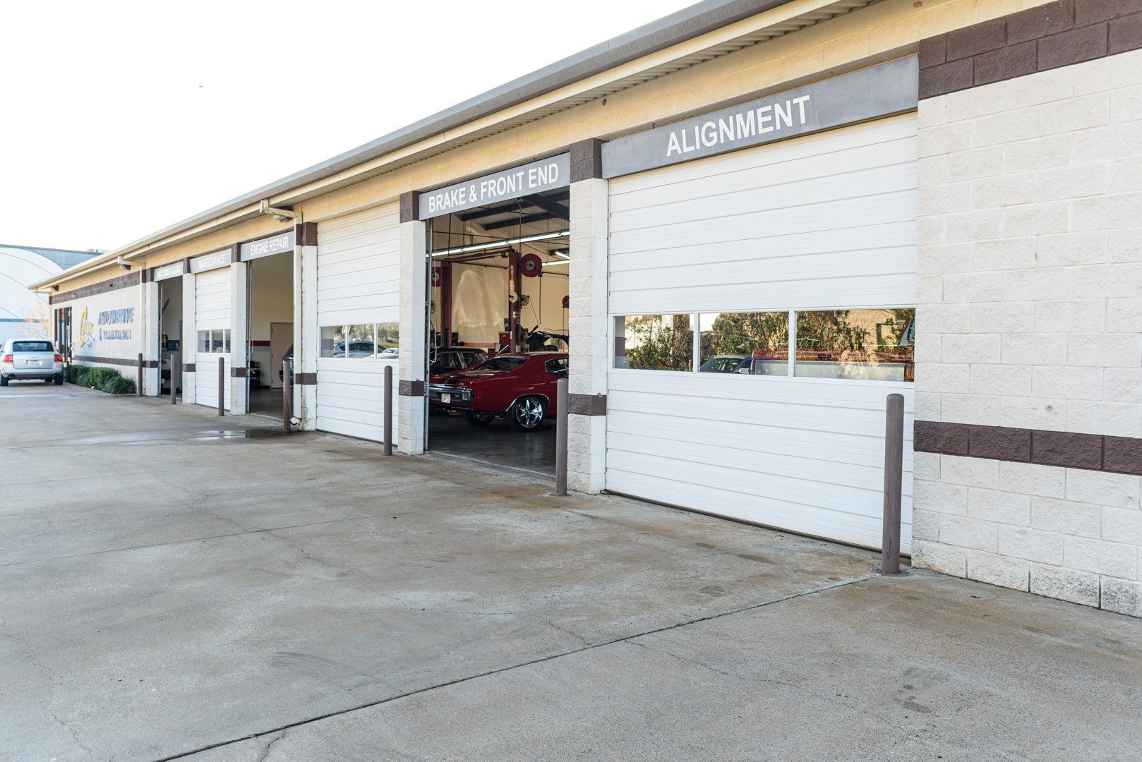 Garage exterior with closed bays, one open with a car on a lift. 