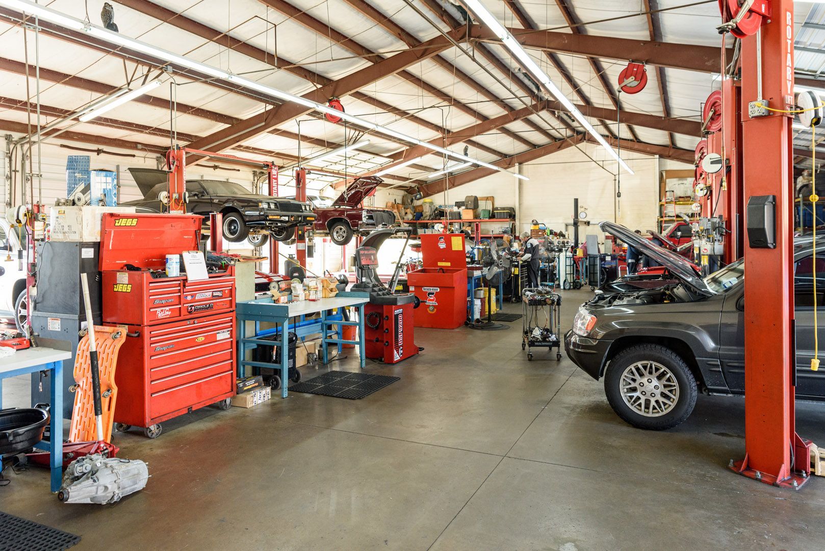 Auto repair shop with tools, lifts, and a car inside a large garage