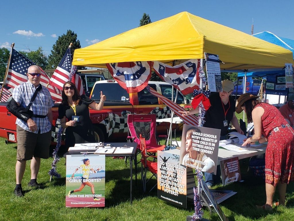 A group of people are standing in front of a tent with american flags on it.