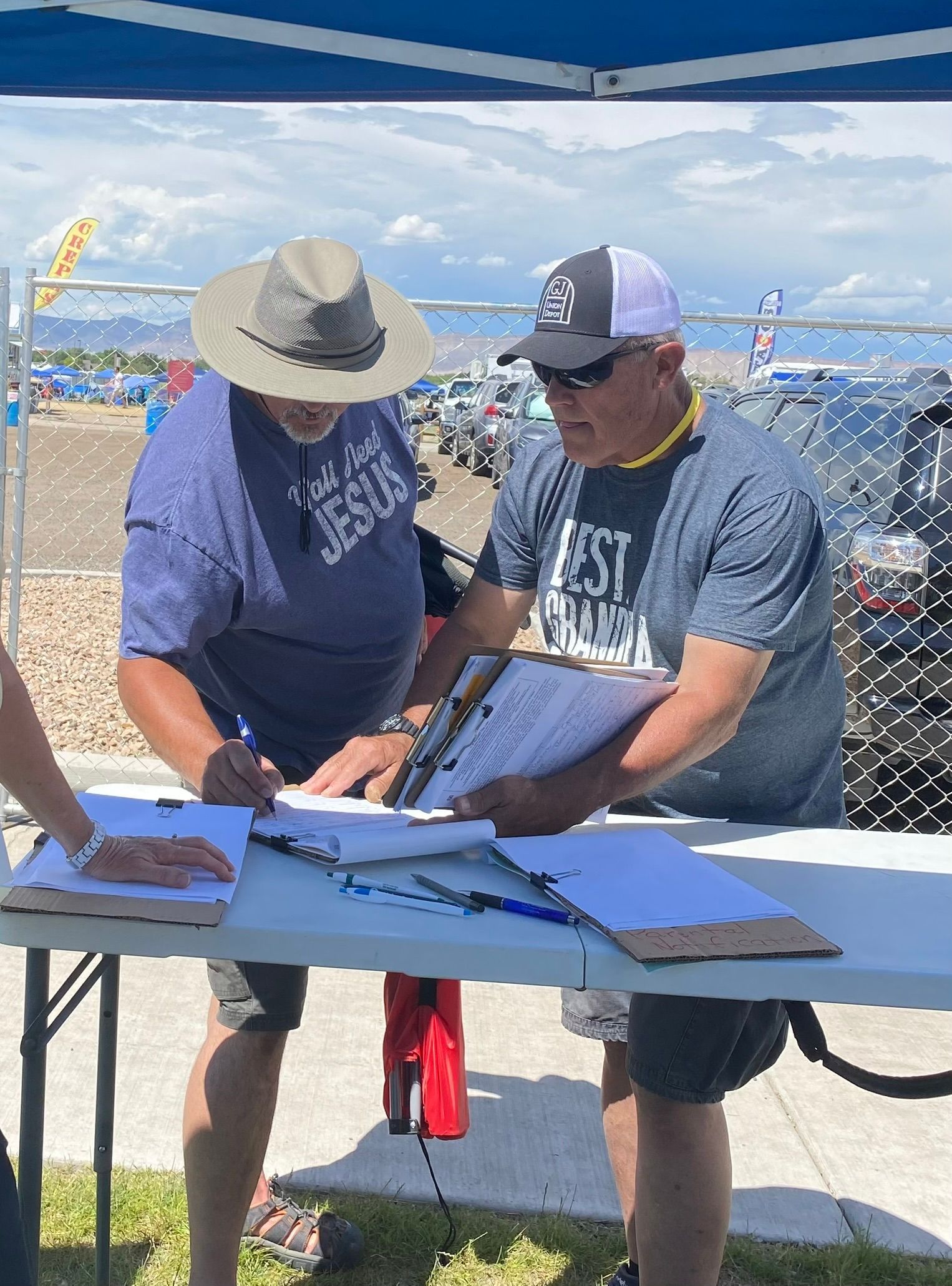 Two men are standing at a table signing papers.