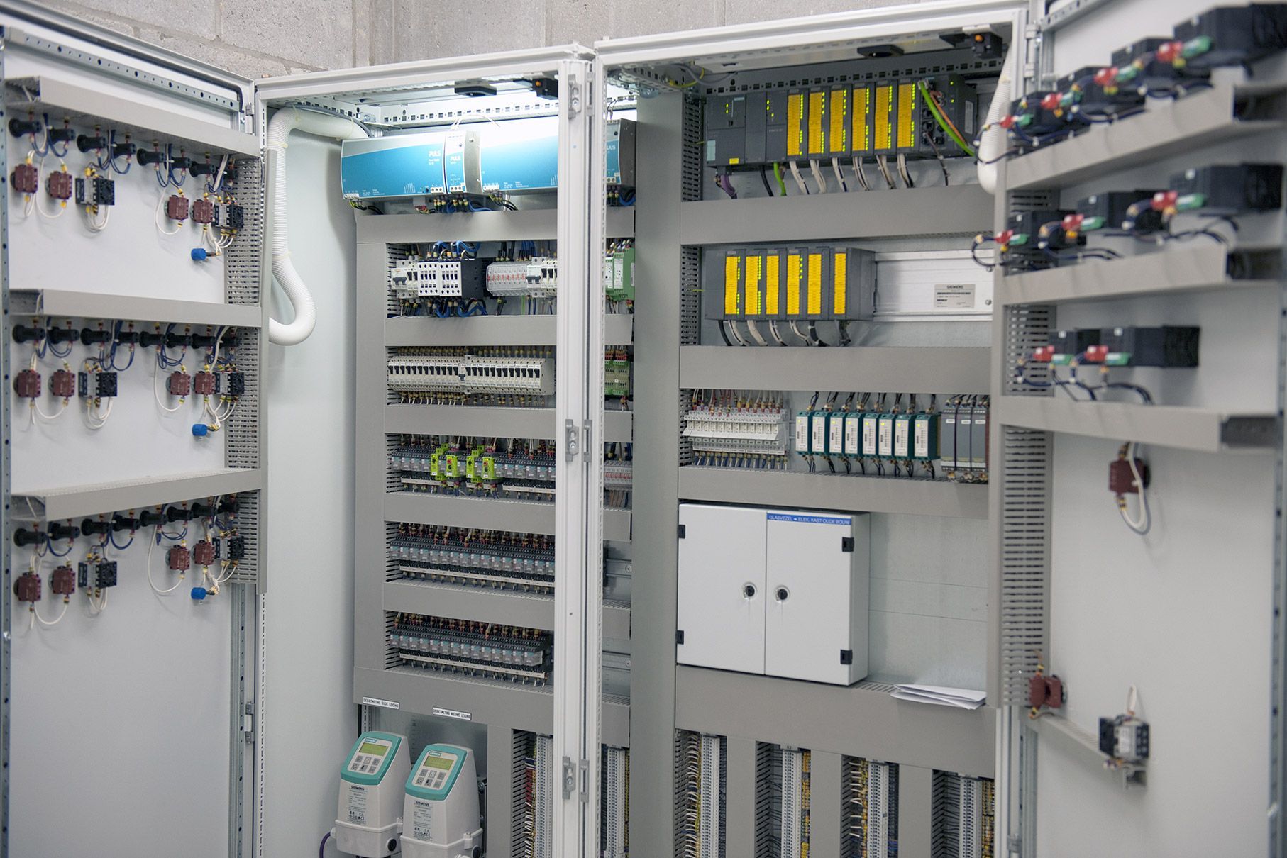 Open elektrische schakelkast met bedrading, circuitmodules en aansluitpanelen erin.