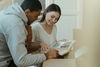 Two people smiling and reading a photo album together on a couch