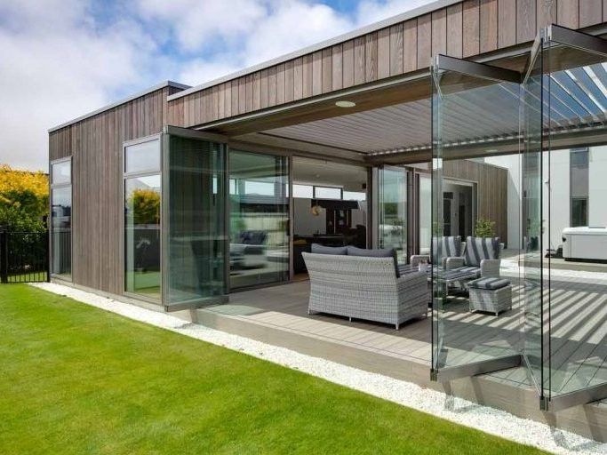 A modern house with a patio and sliding glass doors.