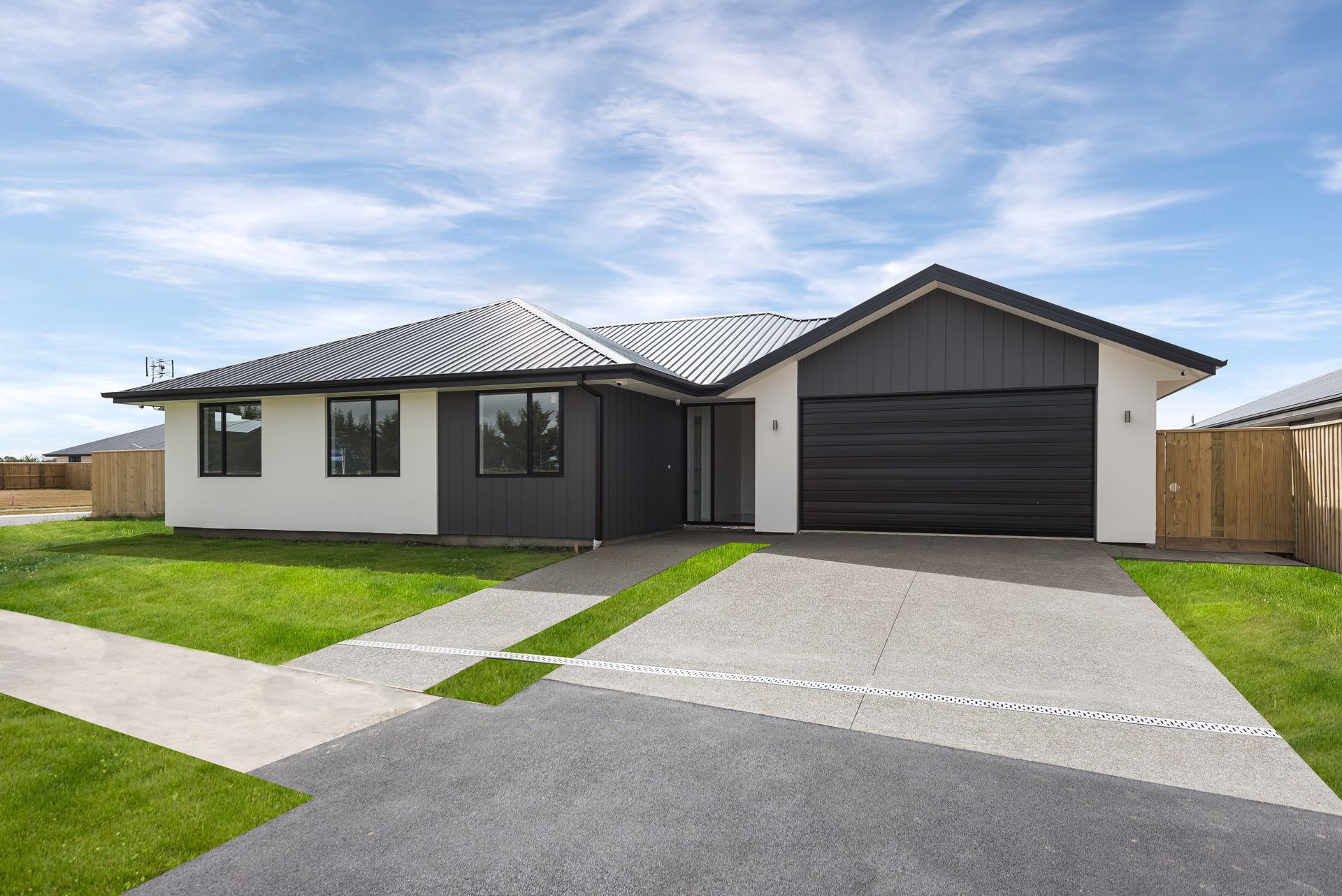 A white and black house with a black garage door and a driveway.