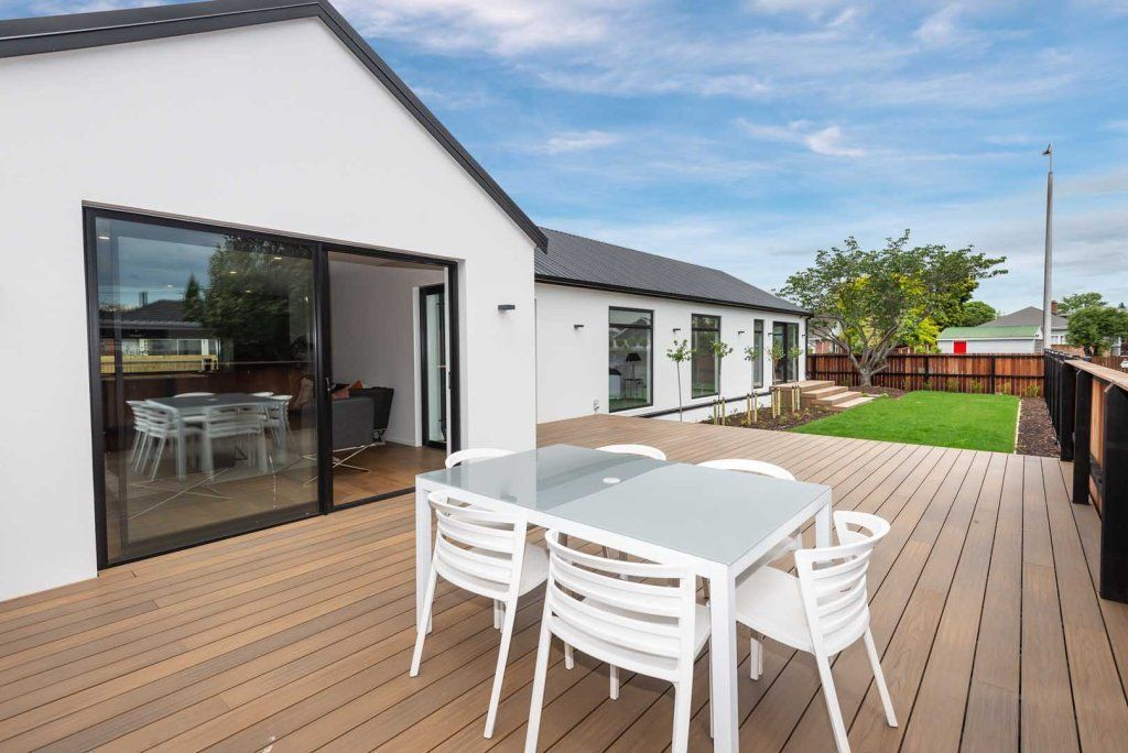 a deck with a table and chairs in front of a house