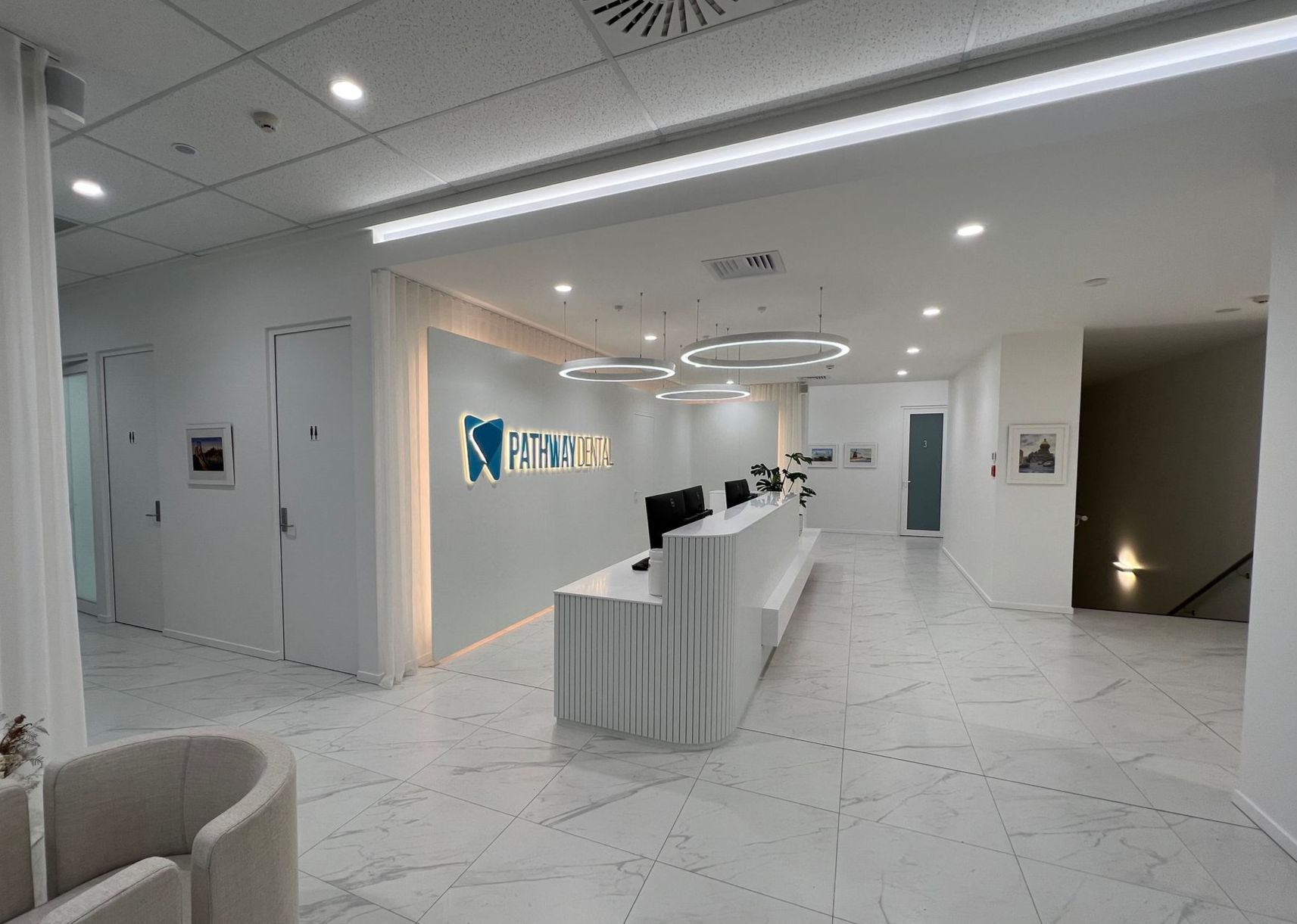 A large white lobby with a reception desk and chairs.