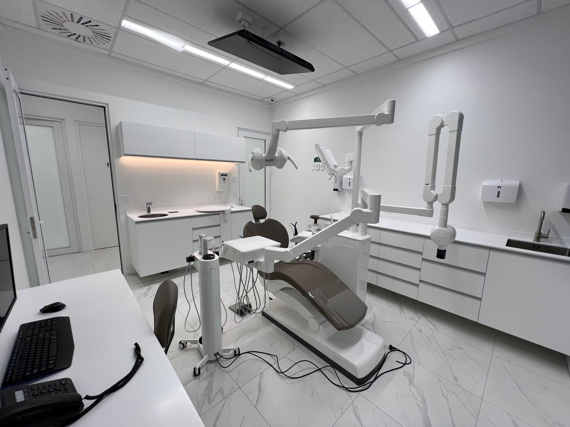A dental office with a dental chair and a desk.