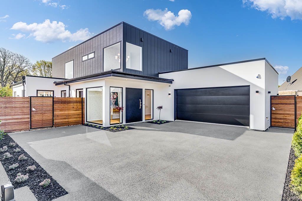 A large white house with a black garage door and a wooden fence.
