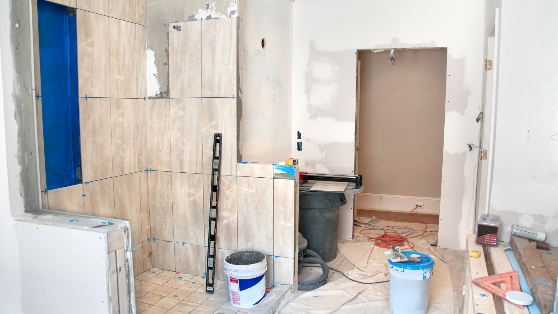 Bathroom under construction with partially tiled walls and blue shower niche.