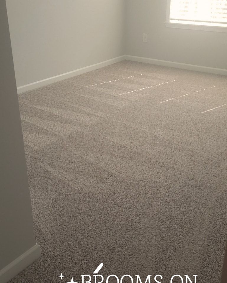 Beige carpeted room, empty. Sunlight streams through window, casting shadows. Gray walls, white baseboards.