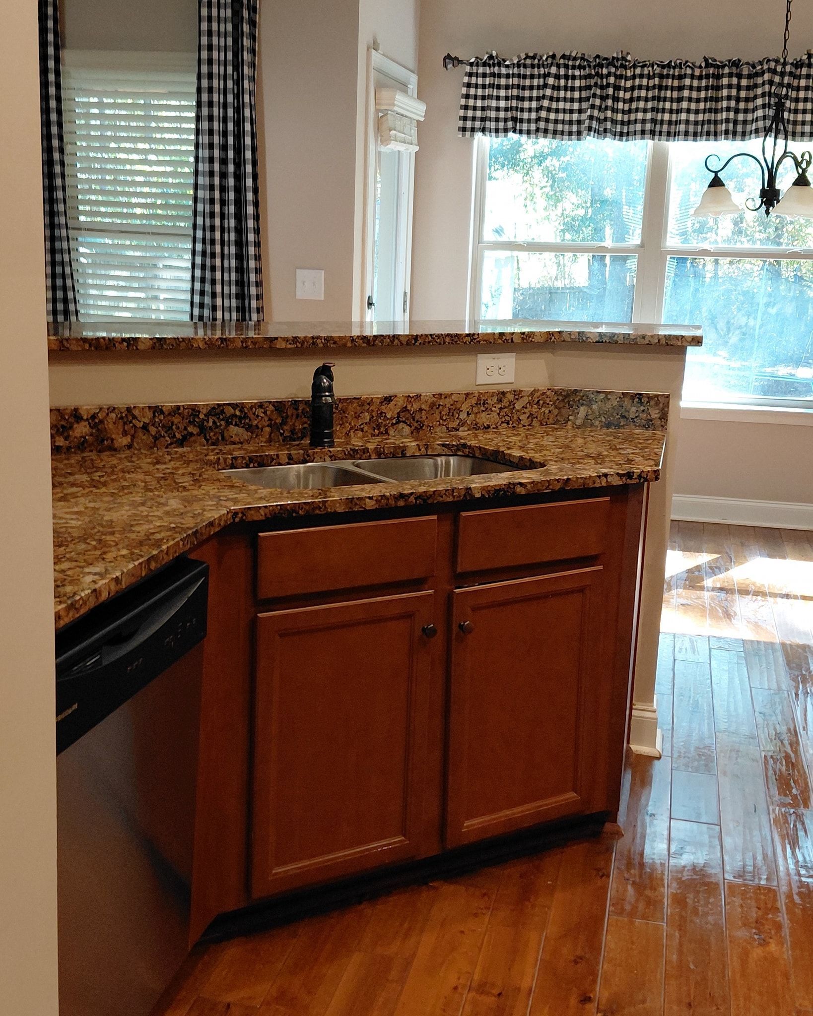 Kitchen with brown cabinets, granite countertops, and a sink. A dishwasher is on the left.