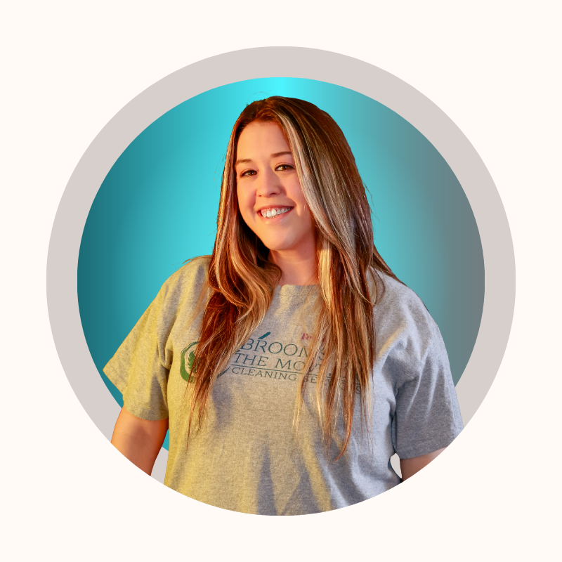 Woman with long hair, wearing a grey t-shirt, smiling, in a circular frame with blue and white background.