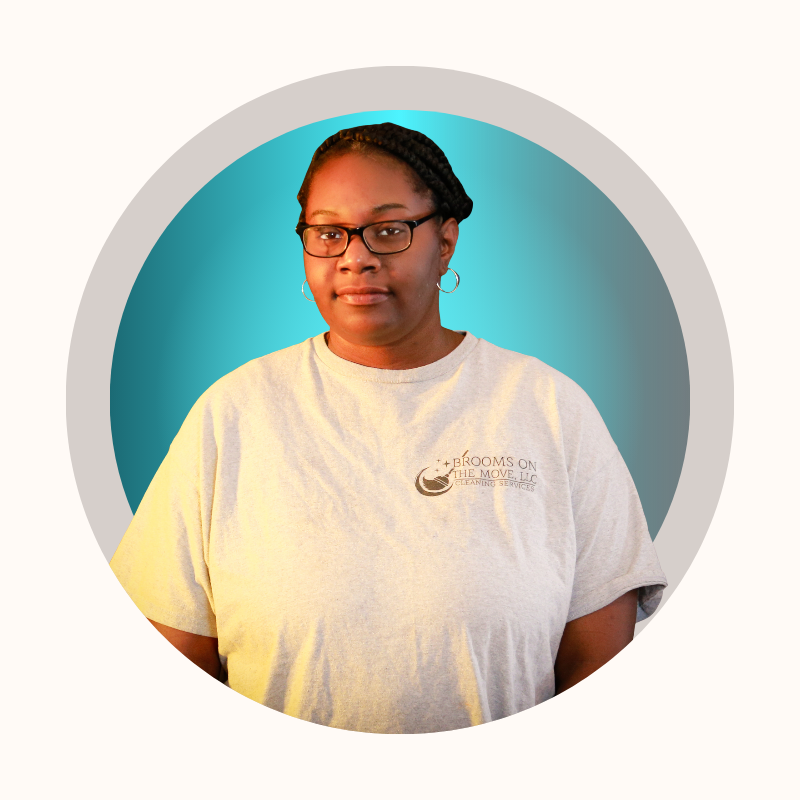 Woman wearing glasses and a t-shirt, stands in front of a blue background inside a round frame.