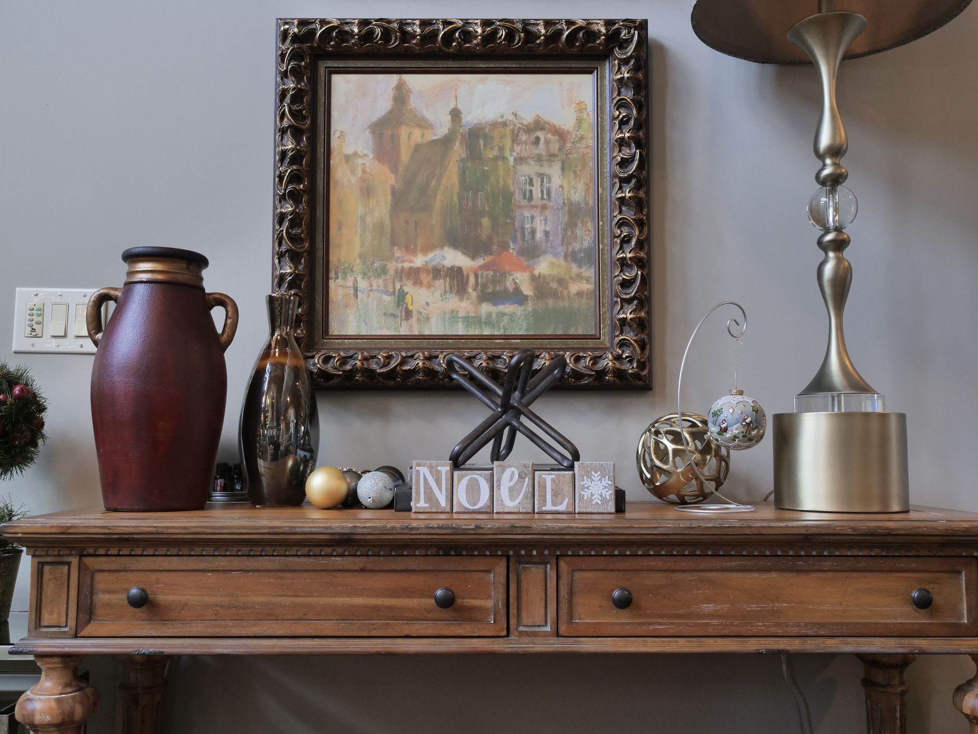 Wooden console table with decor, including a painting, lamp, vase, and 