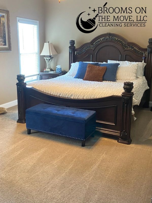 Bedroom with dark wood bed, blue bench, and cream carpet. 