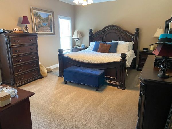 Bedroom with dark wood furniture, a bed with blue and brown pillows, and a blue bench.