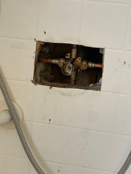 There is a hole in the wall with a hose coming out of it.