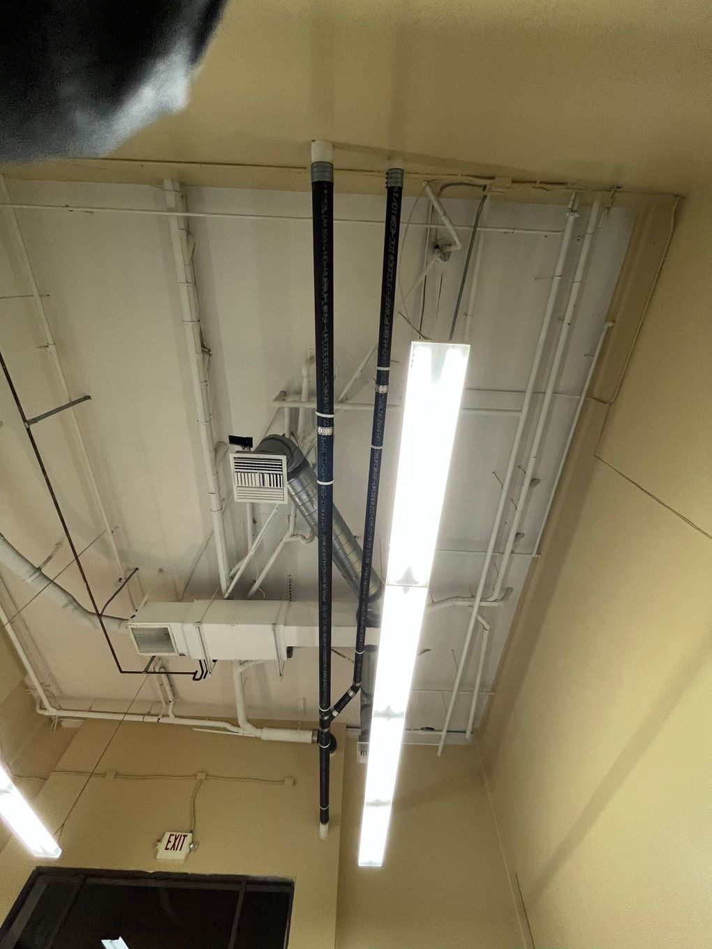 A ceiling with a lot of pipes and lights hanging from it