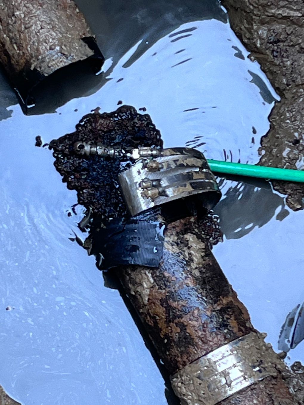 A rusty pipe with a green hose attached to it