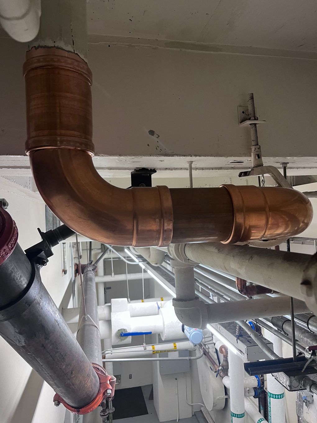 A copper pipe is hanging from the ceiling of a building.