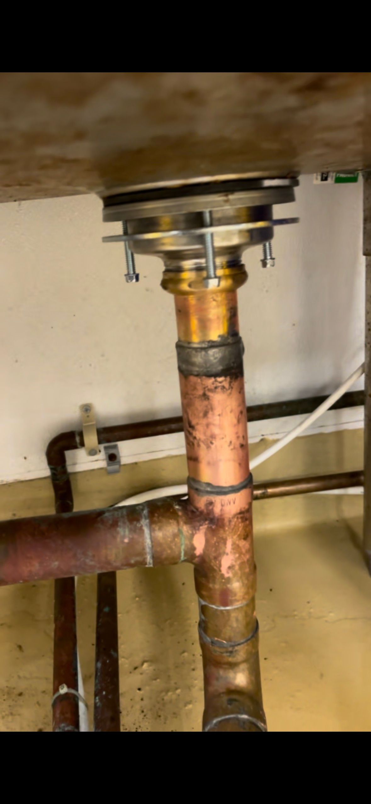 A close up of a copper pipe under a sink.