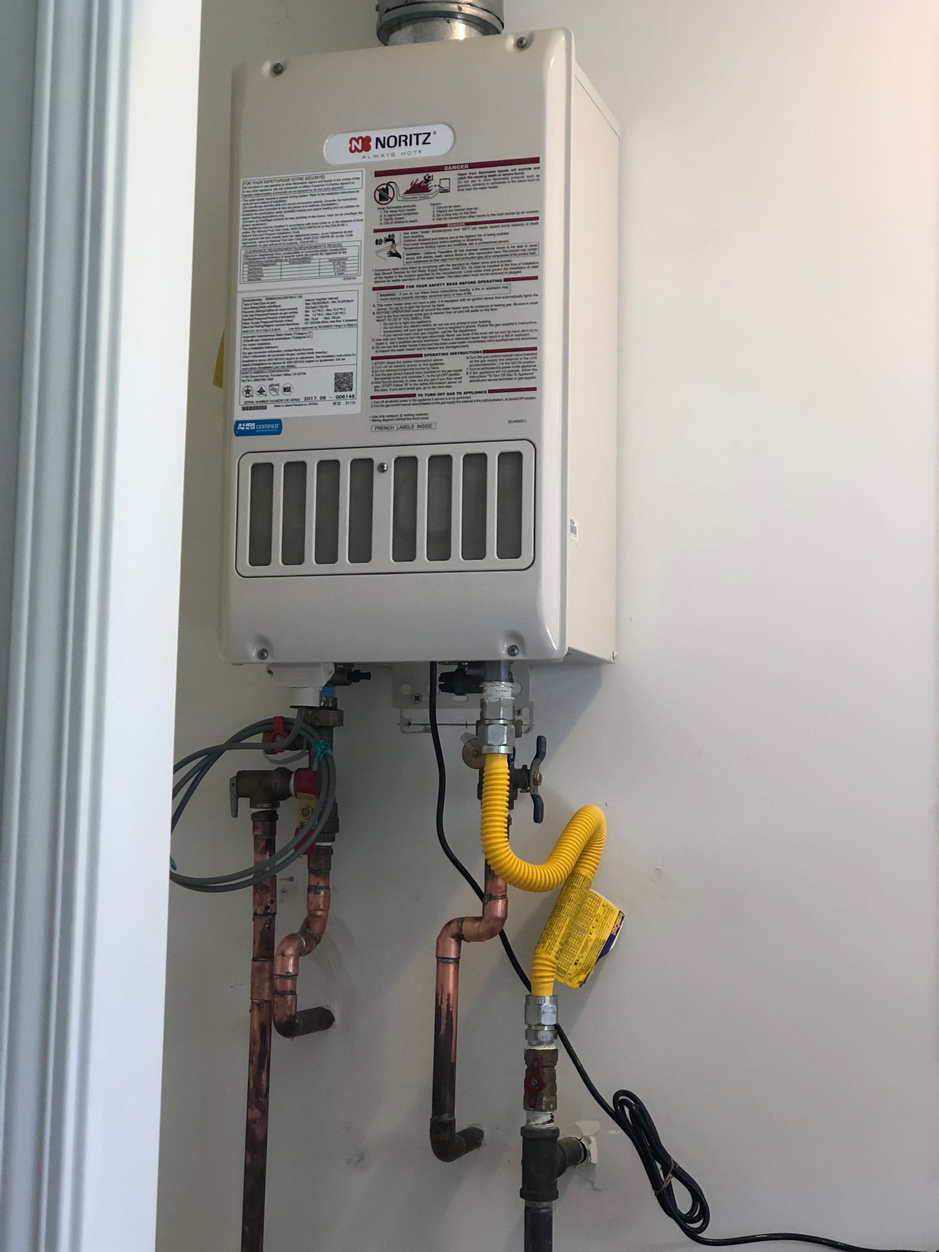 A water heater with a yellow hose attached to it