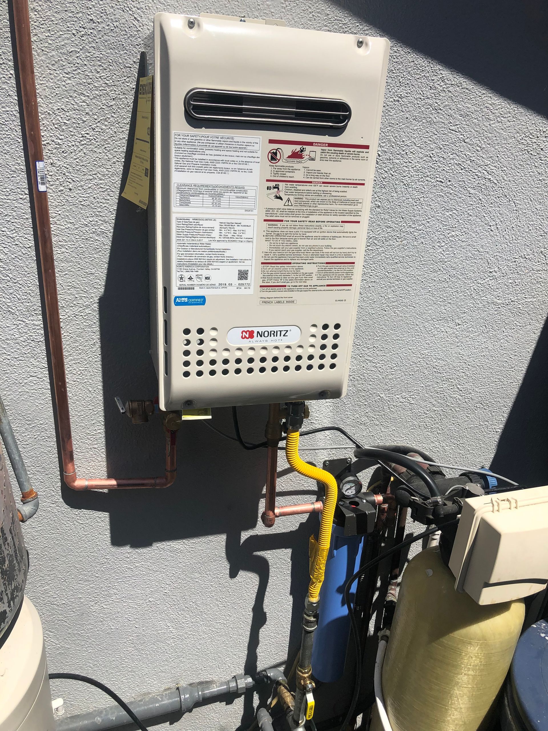 A water heater is attached to a wall next to a water filter.
