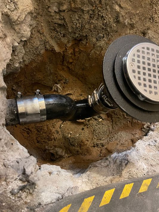 A drain pipe is sitting in a hole in the ground.