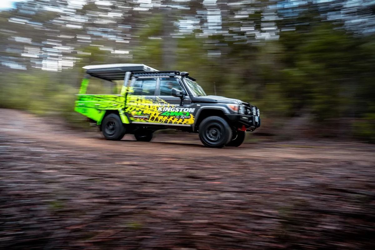 Bright Green Rally Truck Speeding on a Dirt Trail Through a Blurred Forest — Kingston 4wd and Tyres In Huntingfield, TAS