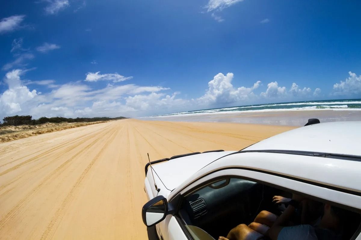 White Car Driving on a Sandy Beach Under a Bright Blue Sky — Kingston 4wd and Tyres In Huntingfield, TAS