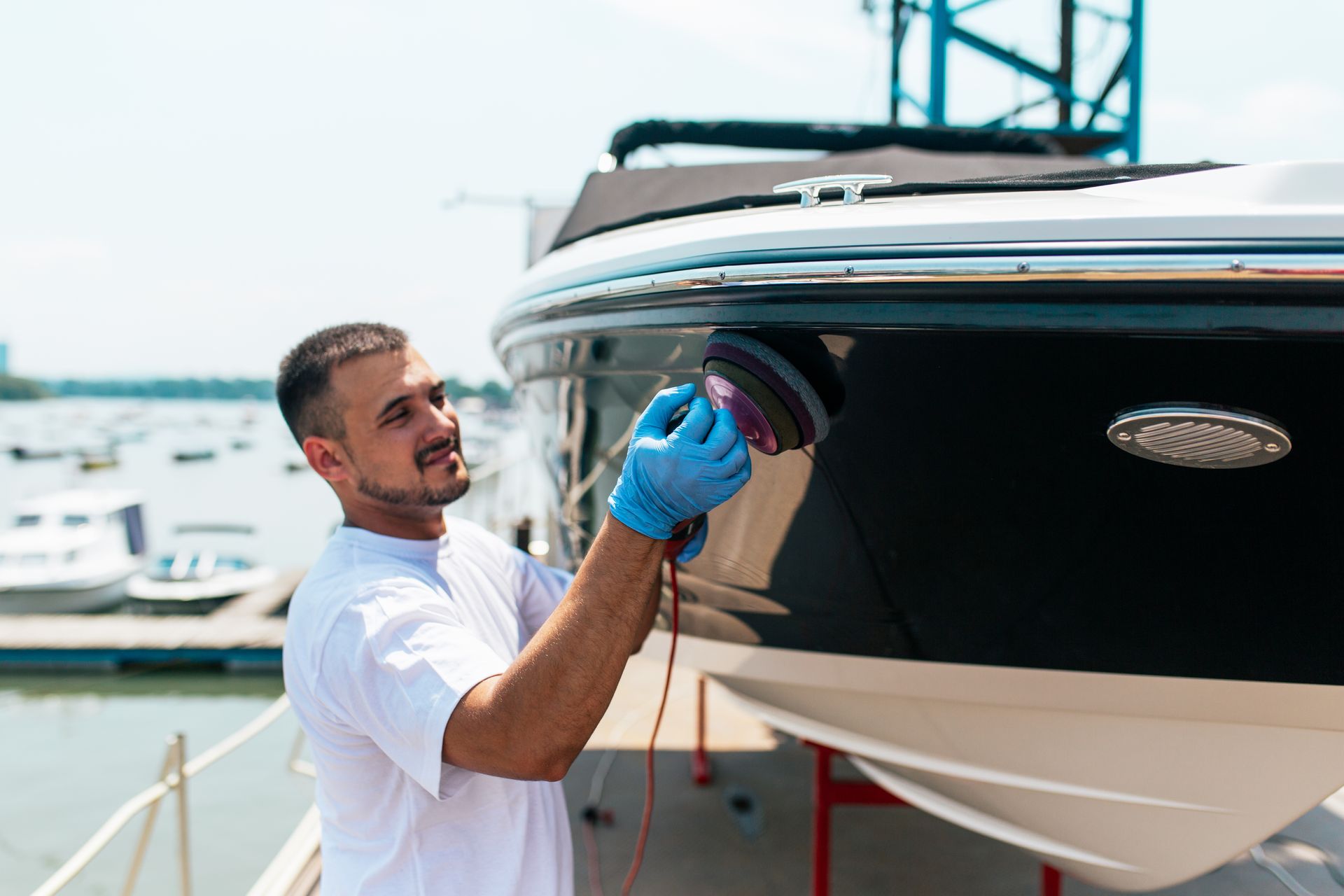 A man is polishing a boat with a machine.