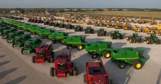 A bunch of tractors are parked in a lot.
