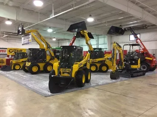 A row of yellow tractors are lined up in a warehouse.