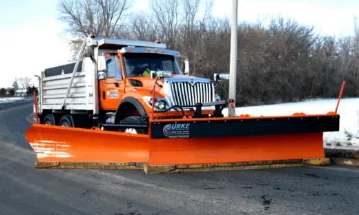 A snow plow is parked on the side of the road.