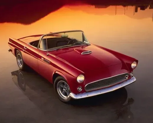 A red convertible is parked in the water at sunset