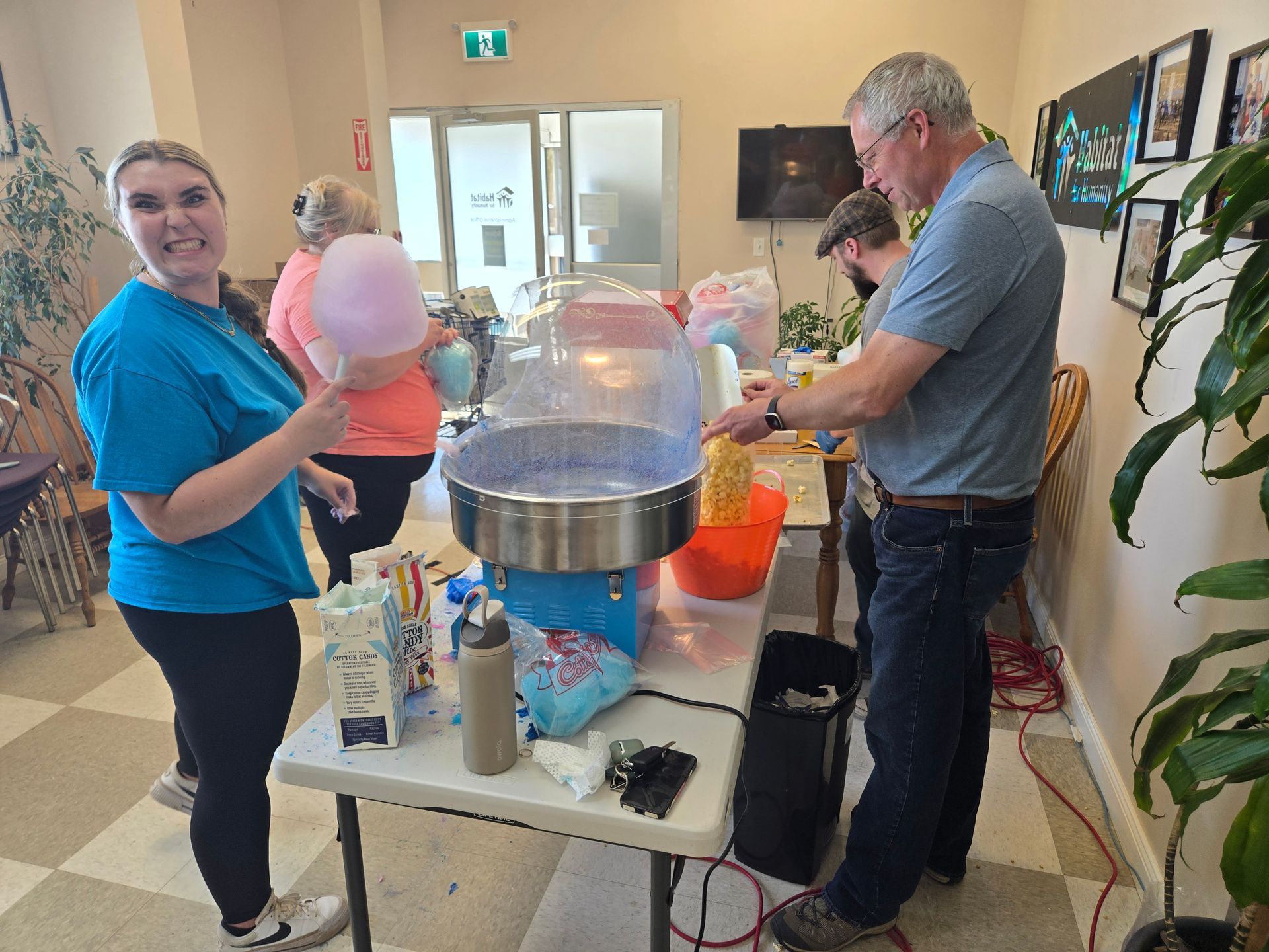 Habitat New Brunswick volunteers and Perry making cotton candy at a table in a bright indoor room