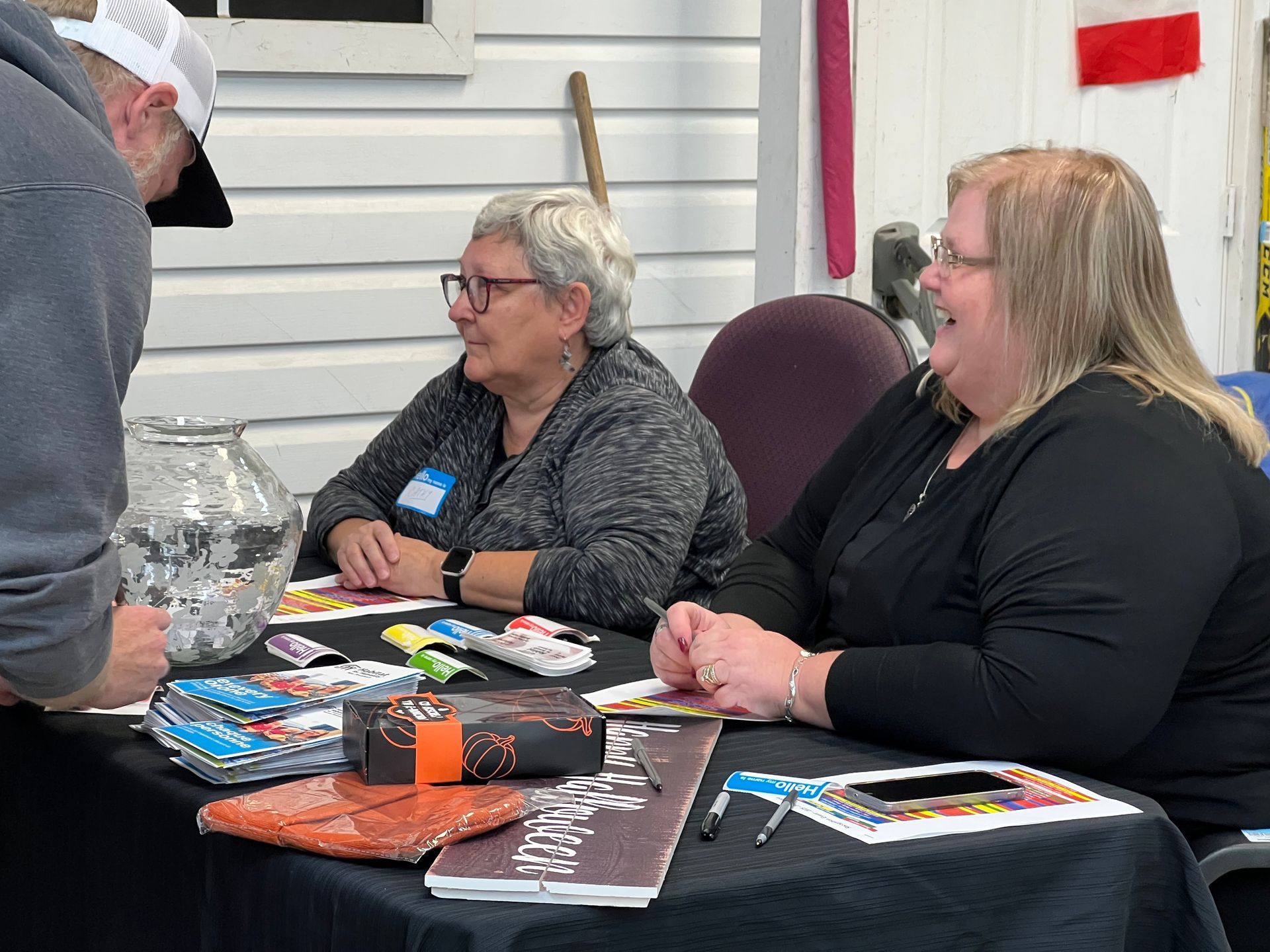 Habitat New Brunswick volunteers - Three people seated at a table with candy and papers at an indoor event