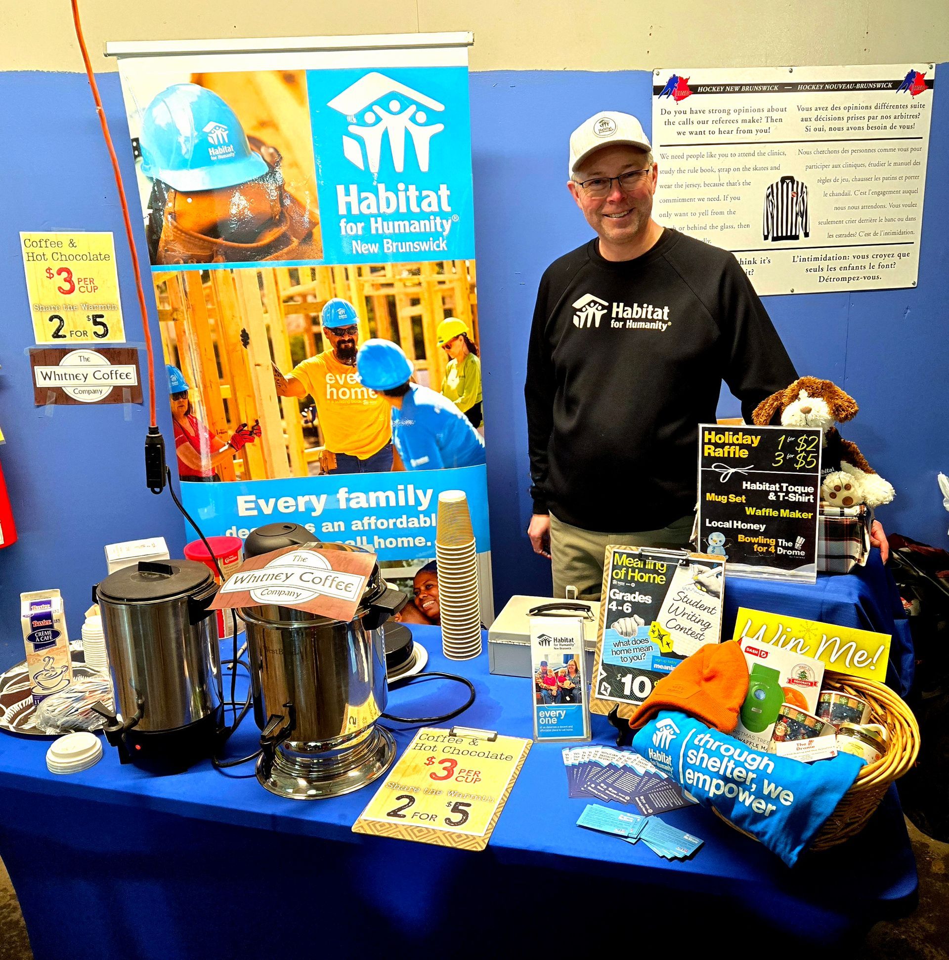 Habitat for Humanity booth with Perry, donation jars, and baked goods on a table