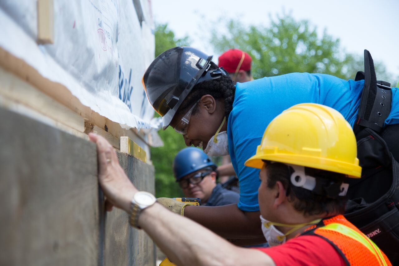 Habitat New Brunswick volunteer Workers in hard hats inspecting and repairing a wall outdoors