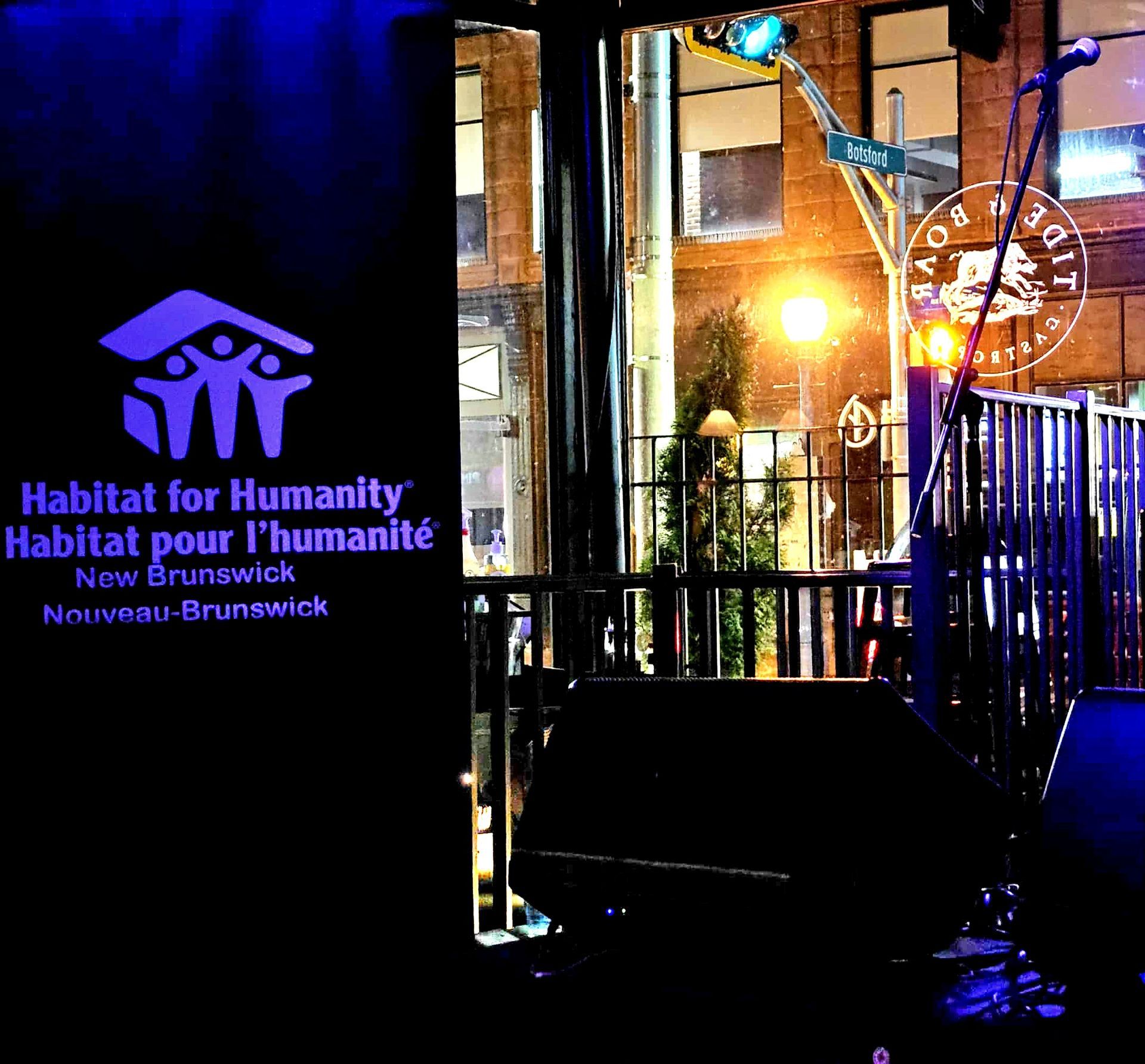 Habitat for Humanity New Brunswick sign beside a lit storefront at night