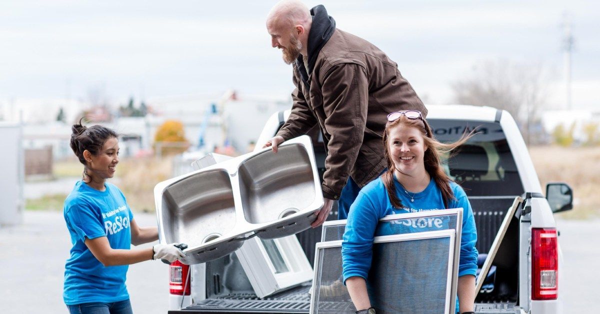 Habitat for Humanity New Brunswick Restore volunteers unloading metal bins from a pickup truck in a parking lot