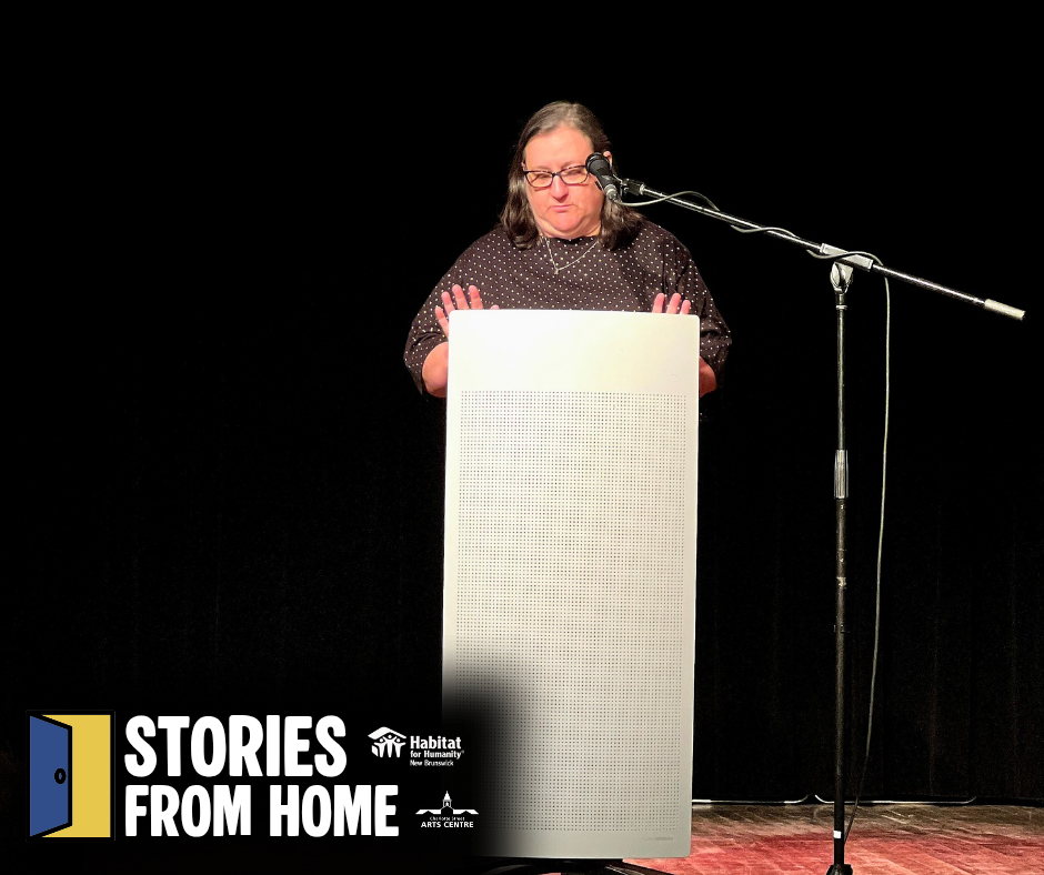 Habitat New Brunswick, Speaker at a podium on a stage, with a microphone and “Stories From Home” sign