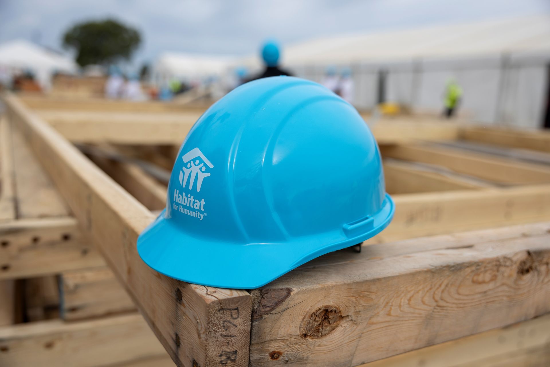 Habitat New Brunswick Blue hard hat on a post in front of a house, with a blurred sign in the background