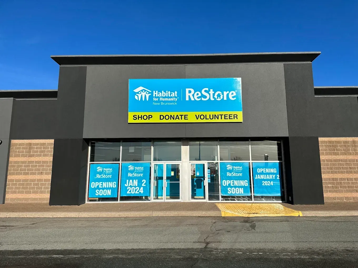 Saint John Habitat for Humanity ReStore storefront with blue signage and “Shop Donate Volunteer” banner