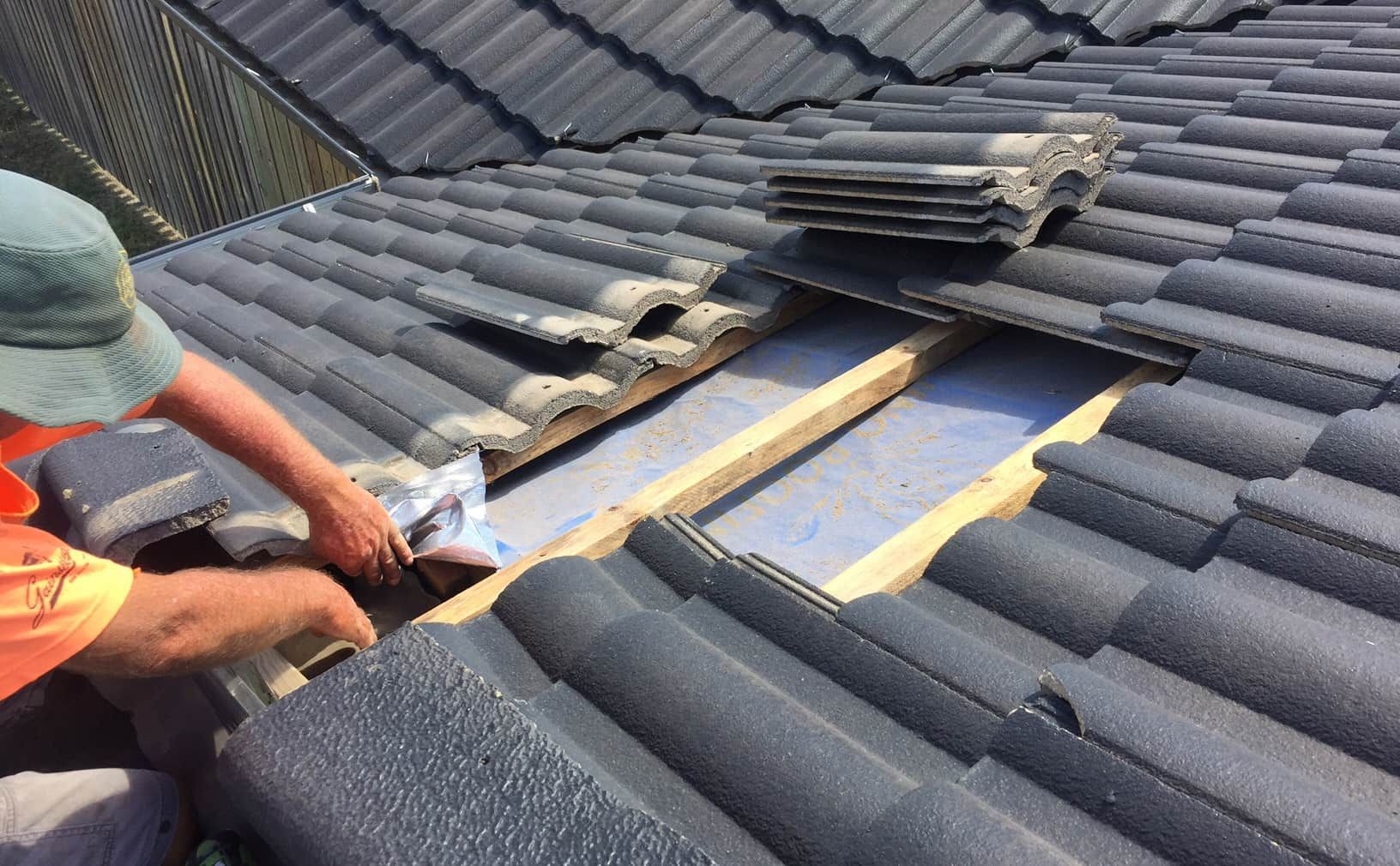 A Man Is Working On The Roof Of A House — Roofpoint In Kawungan, QLD