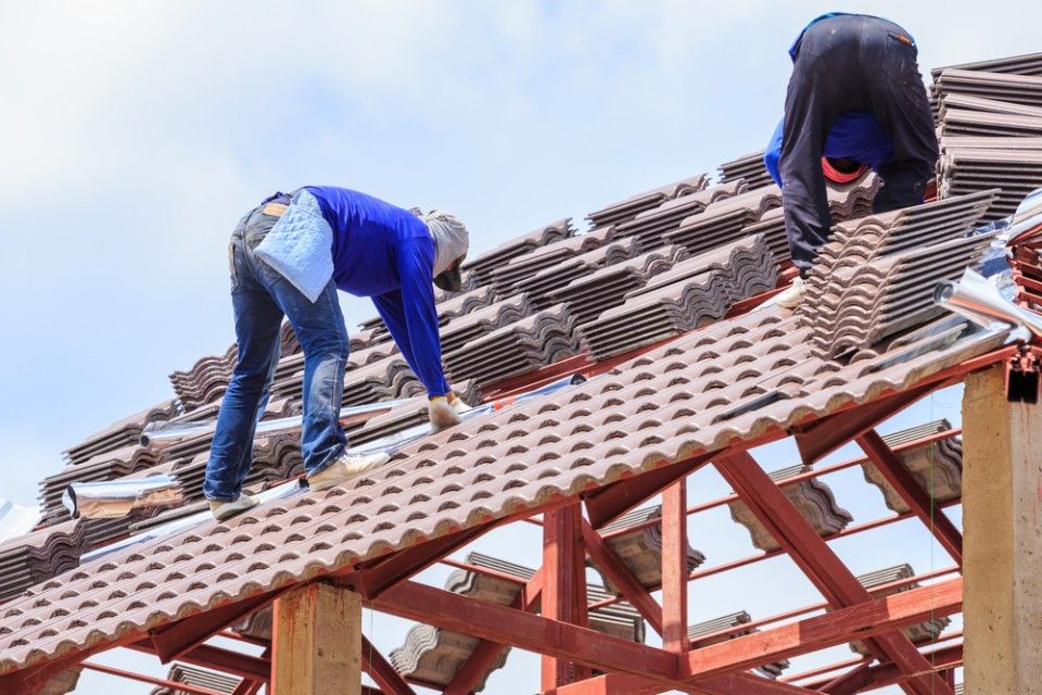 Two Men Are Working on the Roof of a Building — Roofpoint In Kawungan, QLD