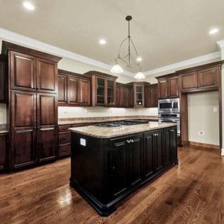 Dark wood kitchen with island, cabinets, appliances, and hardwood floors.